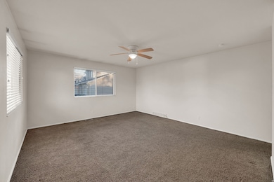 Unfurnished room with dark colored carpet and a ceiling fan