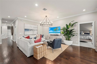 Living room with hardwood / wood-style floors, recessed lighting, a chandelier, baseboards, and crown molding