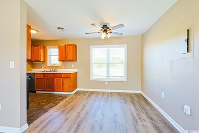 Kitchen with light countertops, brown cabinetry, a ceiling fan, and dark wood-type flooring