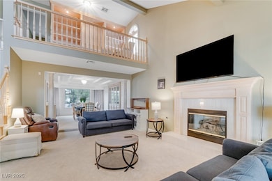 Living room featuring a towering ceiling, a tiled fireplace, beamed ceiling, and carpet