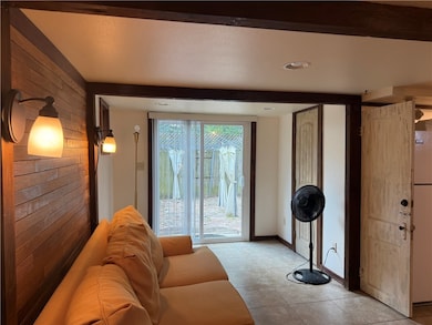 Living room featuring wood walls, tile patterned flooring, beam ceiling, and recessed lighting