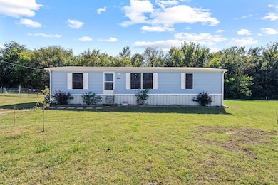 Manufactured / mobile home featuring a front lawn and view of wooded area