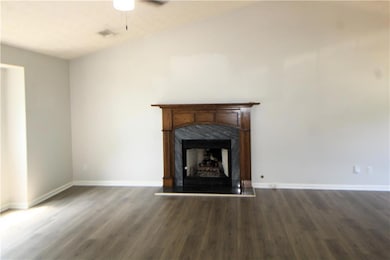 Unfurnished living room featuring a high end fireplace, wood finished floors, and a ceiling fan