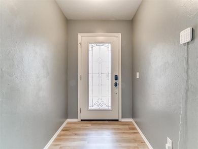 Doorway with light luxury vinyl flooring and baseboards