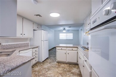 Kitchen with white appliances, visible vents, a pe