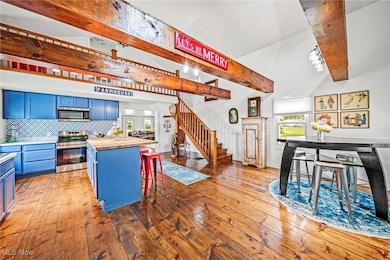 Kitchen featuring blue cabinets, a kitchen bar, stainless steel appliances, wood-type flooring, and butcher block counters