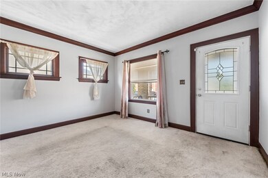 Living room with natural wood crown molding, carpet flooring over hardwood floors