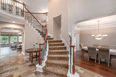 Gorgeous curved staircase with wrought iron spindles, high ceiling and slate flooring in the entry.