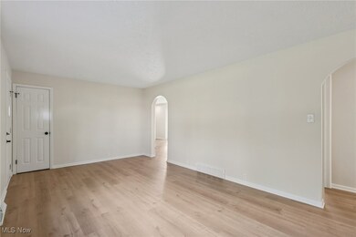Spare room with arched walkways and light wood-style floors