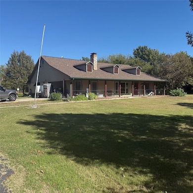 Rear view of house with a lawn, a porch, roof with shingles, and a chimney