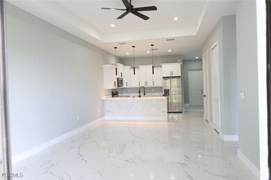 Kitchen featuring stainless steel appliances, white cabinets, a raised ceiling, pendant lighting, and recessed lighting