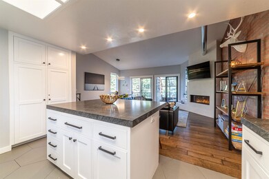 Kitchen featuring dark countertops, a large fireplace, open floor plan, recessed lighting, and white cabinets