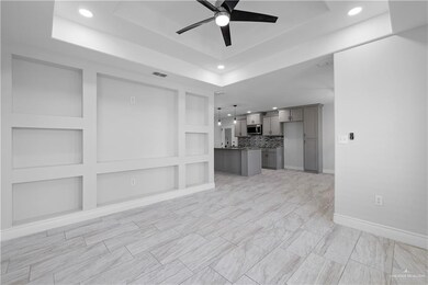 Unfurnished living room featuring ceiling fan, tray ceiling and entertainment wall.