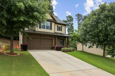 View of front of home featuring a standing seam roof, an attached garage, driveway, a front yard, and brick siding