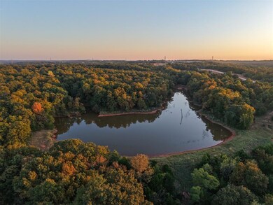 Aerial view of property's location featuring a forest and a nearby body of water