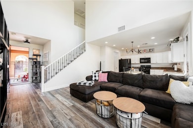 Living room with wood-style floors, stairs, a high ceiling, a chandelier, and recessed lighting