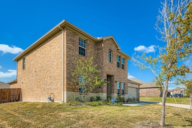 View of home's exterior featuring brick siding, a yard, and a garage