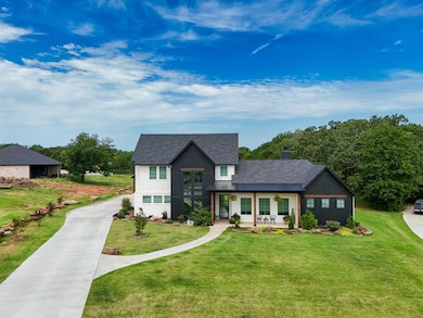 Modern farmhouse style home featuring covered porch, a front lawn, a chimney, a standing seam roof, and roof with shingles