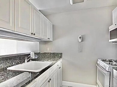 Kitchen featuring white range with gas stovetop, white cabinets, and stainless steel microwave