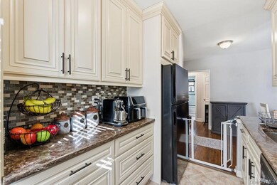 Kitchen with freestanding refrigerator, dark stone counters, cream cabinets, and backsplash