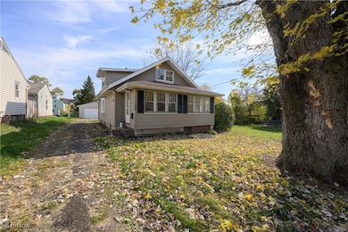 Bungalow-style house featuring an enclosed front porch, a front yard, and a detached garage