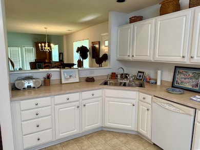 Kitchen featuring dishwasher, a chandelier, light countertops, white cabinets, and pendant lighting