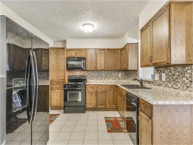 Completely remodeled, the kitchen has new tile floors, updated cabinet storage, countertops, tile backsplash, and modern appliances.
