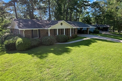 Single story home with brick siding, driveway, a front lawn, and an attached carport