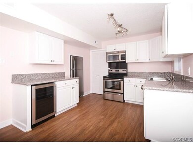 The kitchen has hardwood floors and is updated with granite countertops, granite backsplash, stainless steel appliances, white cabinetry, and large pantry.