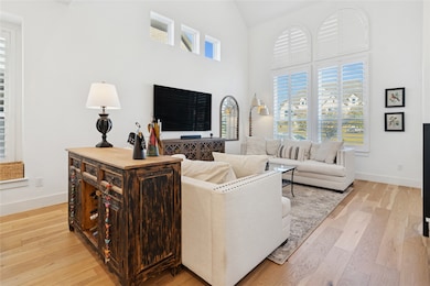 Living area with light wood-type flooring and high vaulted ceiling