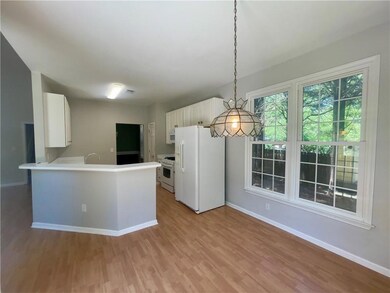 Kitchen featuring white appliances, baseboards, light wood-style floors, white cabinetry, and light countertops