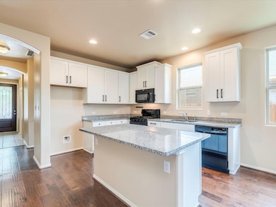 Kitchen with black appliances, a kitchen island, 