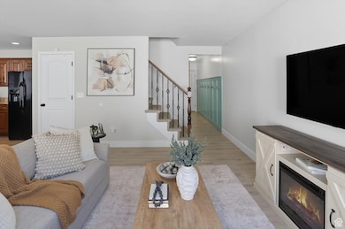 Living room with light wood finished floors, stairway, and a glass covered fireplace