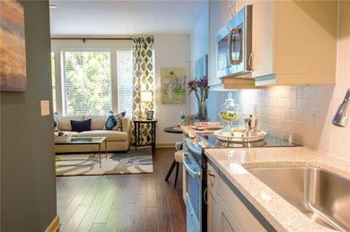Kitchen with white cabinetry, stainless steel appliances, dark hardwood / wood-style floors, and decorative backsplash