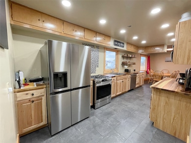 Kitchen featuring appliances with stainless steel finishes, recessed lighting, light brown cabinetry, open shelves, and butcher block countertops