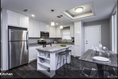 Kitchen with a kitchen island, visible vents, appliances with stainless steel finishes, open shelves, and white cabinetry