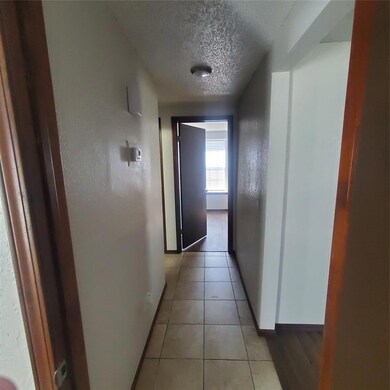 Hall featuring a textured ceiling and light tile p