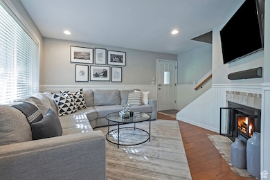 Living room with wood finished floors, a wainscoted wall, recessed lighting, and a tiled fireplace