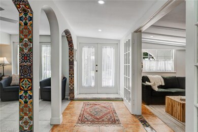 Entryway with french doors, arched walkways, light tile patterned floors, lofted ceiling, and recessed lighting