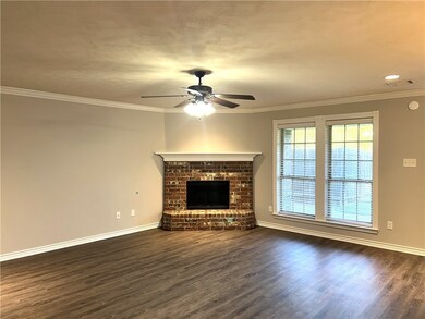 Unfurnished living room featuring ceiling fan, crown molding, dark hardwood / wood-style floors, and a brick fireplace