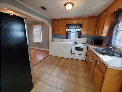 Kitchen with freestanding refrigerator, white electric stove, a sink, washer and dryer, and light countertops