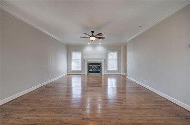 Unfurnished living room with wood finished floors, baseboards, a fireplace, ornamental molding, and ceiling fan