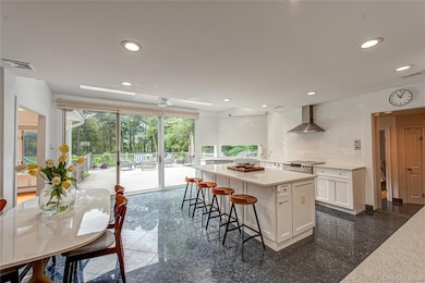 Kitchen featuring white cabinets, granite tiled floors, exhaust hood, recessed lighting, and a kitchen island