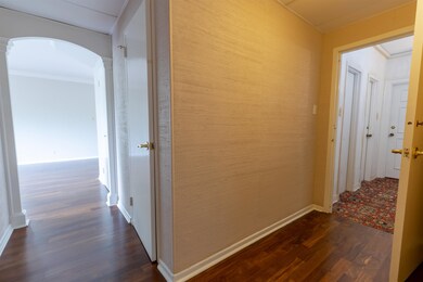 Corridor featuring ornamental molding and dark woo