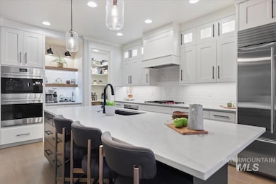 Kitchen featuring white cabinets, a breakfast bar area, light stone countertops, appliances with stainless steel finishes, and recessed lighting