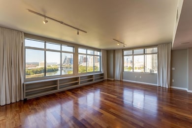 Empty room with rail lighting, a view of city, wood finished floors, and a water view