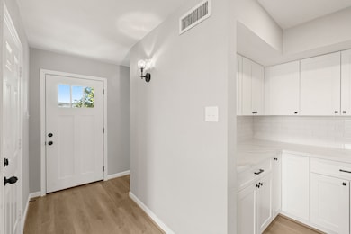 THE FOYER PROVIDES ACCESS TO THE HOME, AND A PEEK AT THE ADJACENT, NEWLY UPDATED KITCHEN CABINETRY.