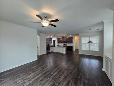 Unfurnished living room with dark wood-style floors, a ceiling fan, baseboards, ornamental molding, and recessed lighting