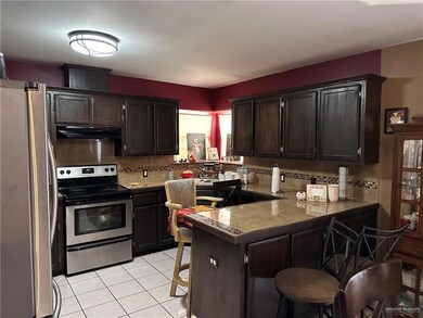 Kitchen featuring decorative backsplash, appliances with stainless steel finishes, kitchen peninsula, and a kitchen breakfast bar