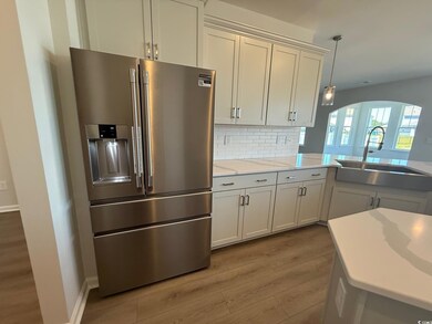 Kitchen with high end fridge, a sink, wood finished floors, arched walkways, and tasteful backsplash